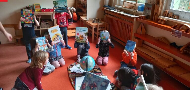 Kinder sitzen im Kreis und halten ihre Lieblingsbücher hoch.