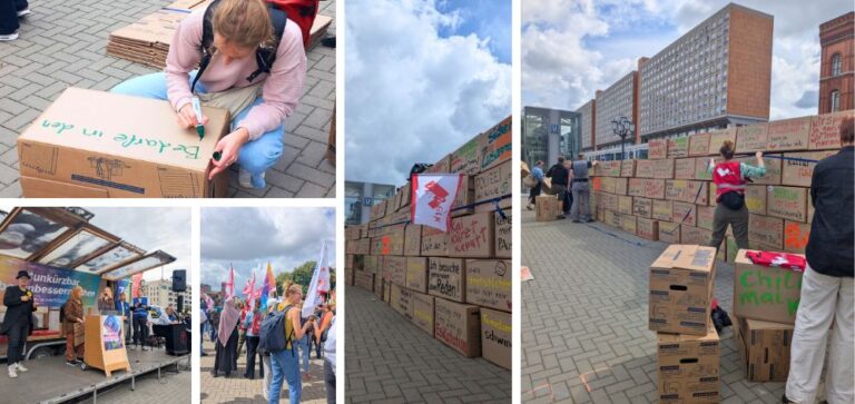 Menschen schreiben Botschaften auf Pappkartons und stapeln sie vor dem Roten Rathaus zu einer Mauer.